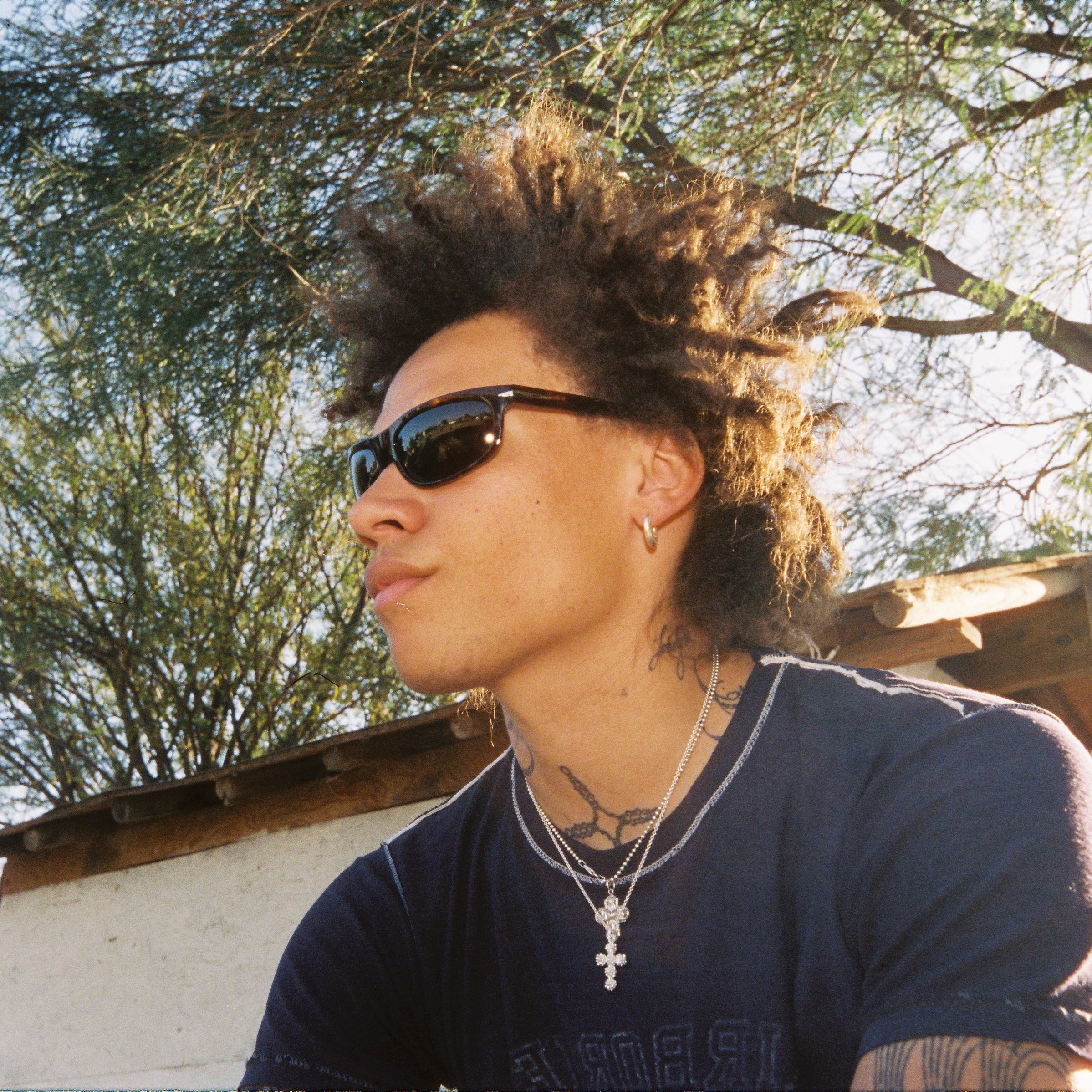 Person with sunglasses and styled hair outdoors with trees in the background. Sad Eyewear Polarized Tortoise HEAT