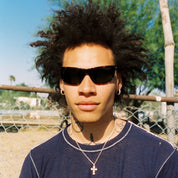 Person wearing sunglasses and a blue t-shirt with a graphic design, standing outdoors. Sad Eyewear Polarized Tortoise Sunglasses