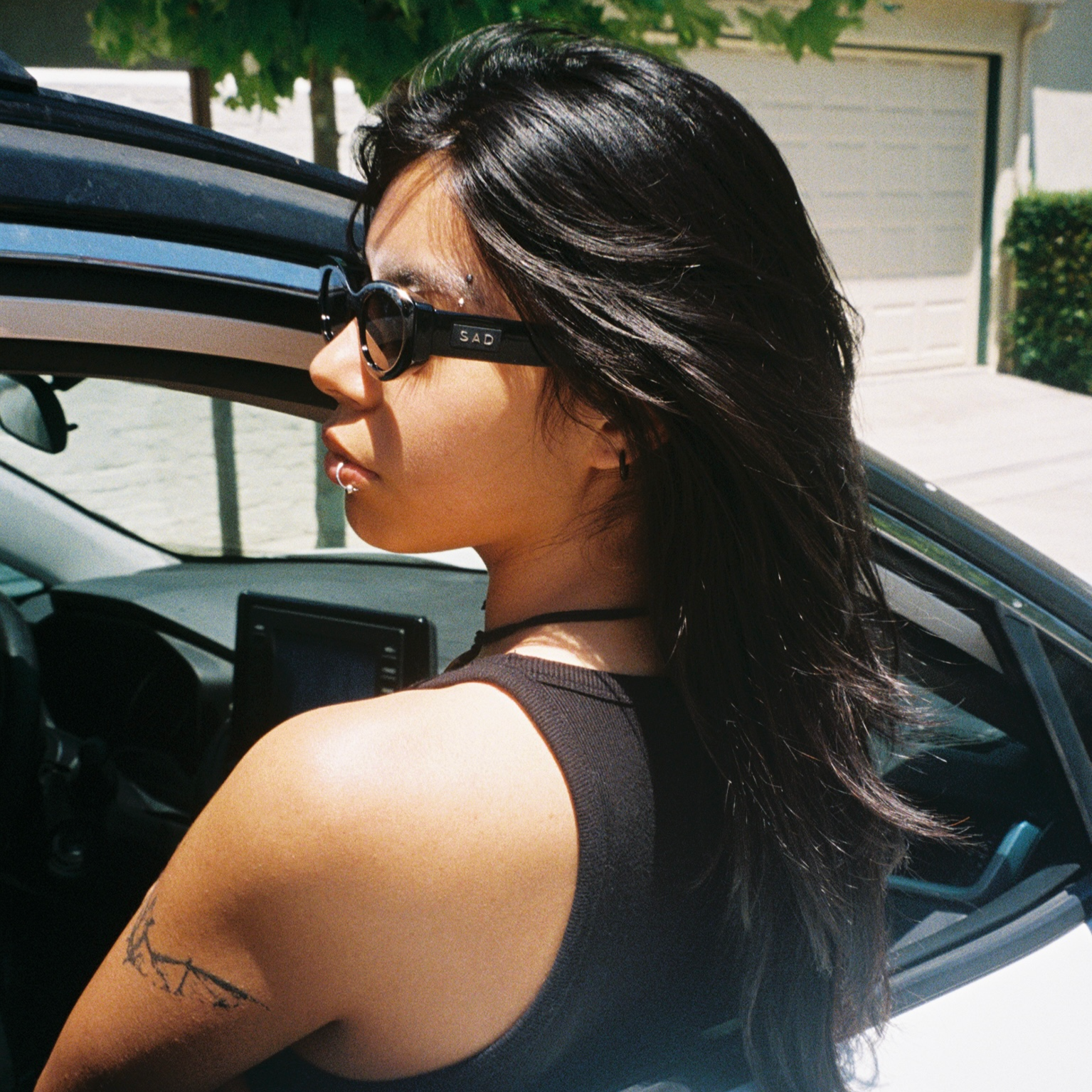 Woman sitting in a car with sunglasses on, looking out the window.