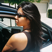 Woman sitting in a car with sunglasses on, looking out the window.