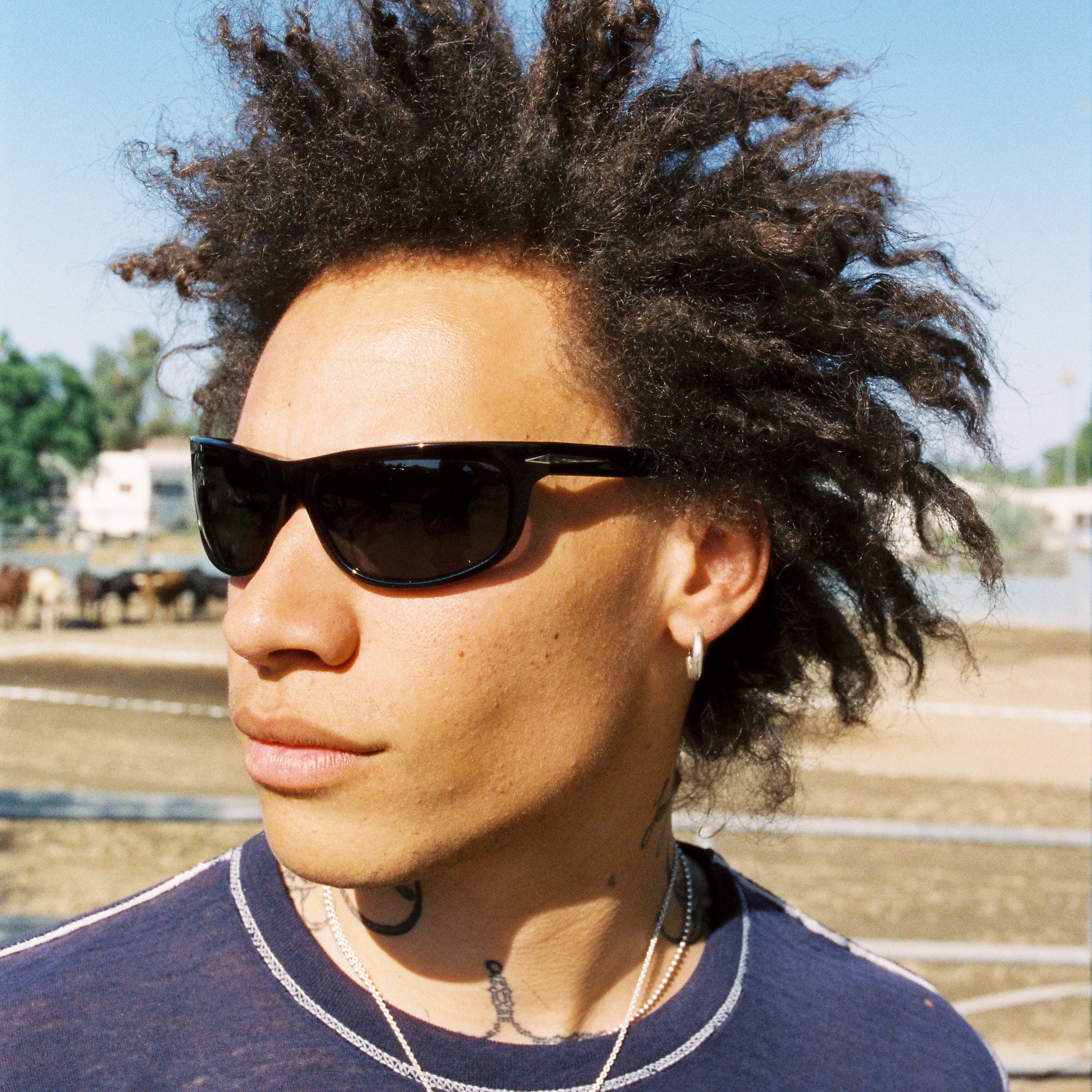 Person with styled hair wearing sunglasses outdoors