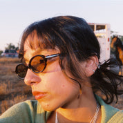 Woman wearing sunglasses with a horse and trailer in the background