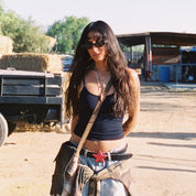 Woman standing outdoors with a truck and hay bales in the background