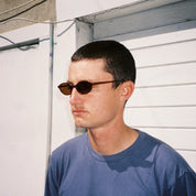 Zachary Kovacs wearing SAD Eyewear Celeste oval sunglasses in tobacco with polarized bronze UV protection lenses